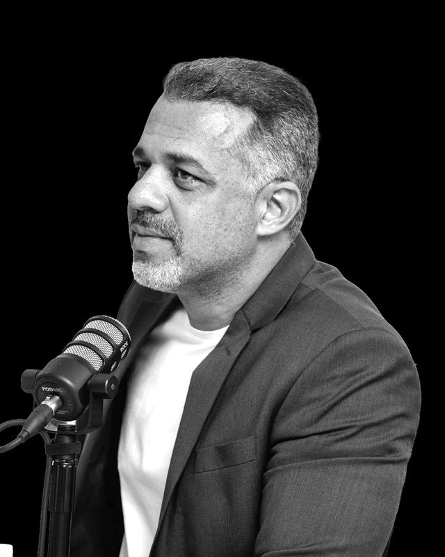 Emerson Teixeira ao microfone num podcast, em preto e branco