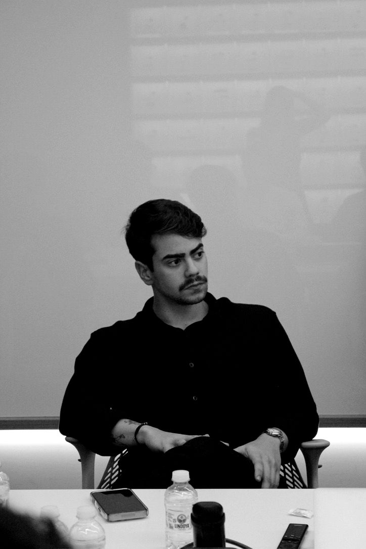 Gabriel numa reunião, sentado à mesa, em preto e branco